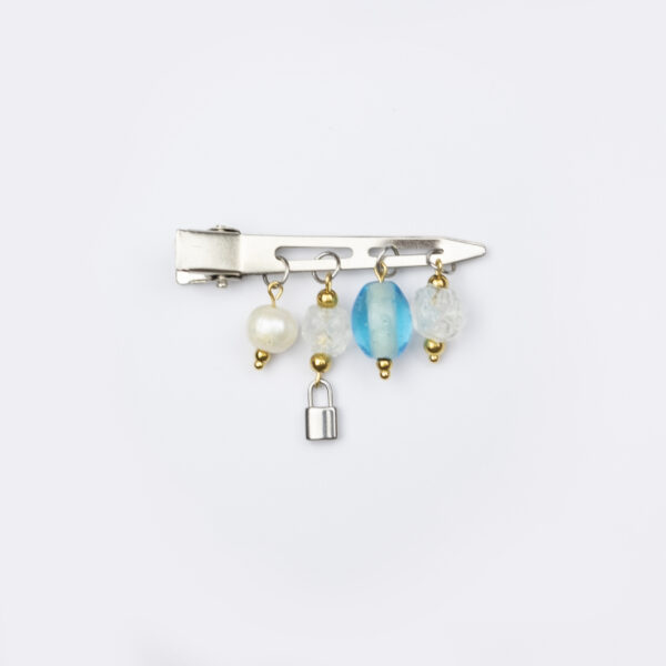 BB {Bijoux Barrettes} en acier inoxydable composée d'une barrette plate argenté, d'une perle de culture, de perles doré et de perles en verre bleues et transparentes et d'un cadenas argenté