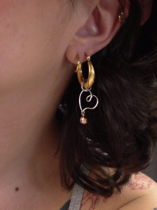 Mono boucle d’oreilles en acier inoxydable composée d'une créole doré, d'un coeur en laiton plaqué argent et d'un oxyde de zirconium rose