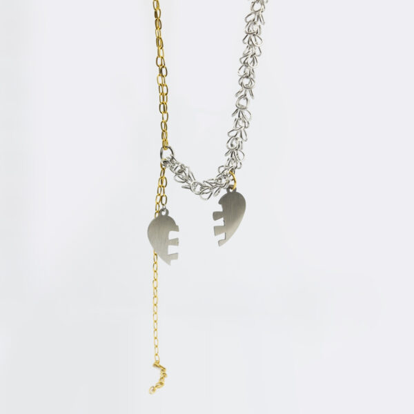 Collier en acier inoxydable. Il s'agit d'un collier composé d'une double chaine doré et d'une chaine argenté ainsi que de deux moitiés de coeur