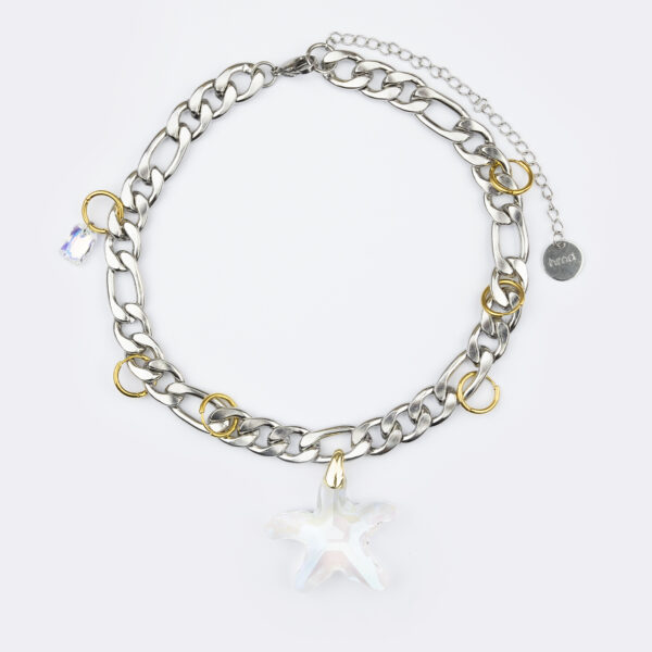 Collier en acier inoxydable. Il s'agit d'un collier composé d'une chaine épaisse argenté, de plusieurs anneaux doré et d'un pendentif étoile transparent de seconde main