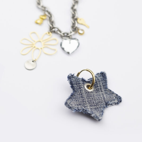 Collier en acier inoxydable. Il s'agit d'un composé d'une chaine argenté, et de multiples pendentifs doré aux formes diverses en acier, cristal et jean