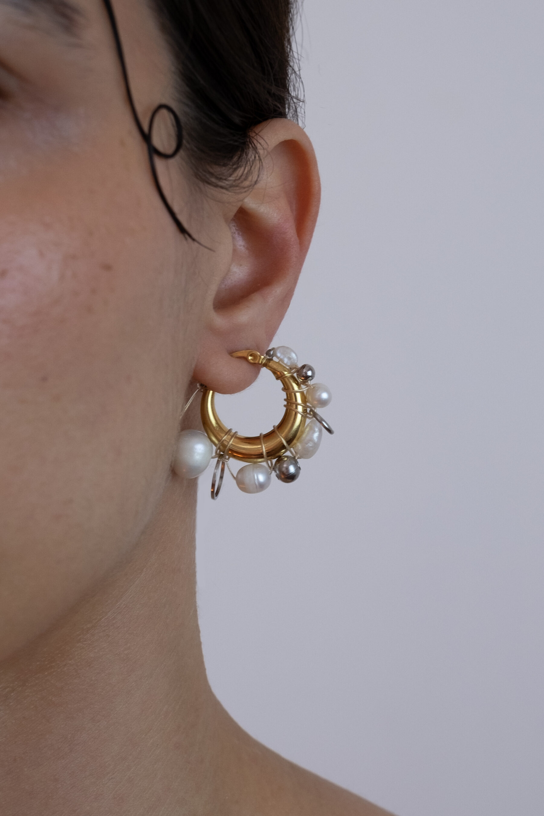 Mono boucle d’oreilles en acier inoxydable composée d’une créole dorée, de perles de culture et d'anneaux argentés de différentes tailles tressés autour de la boucle