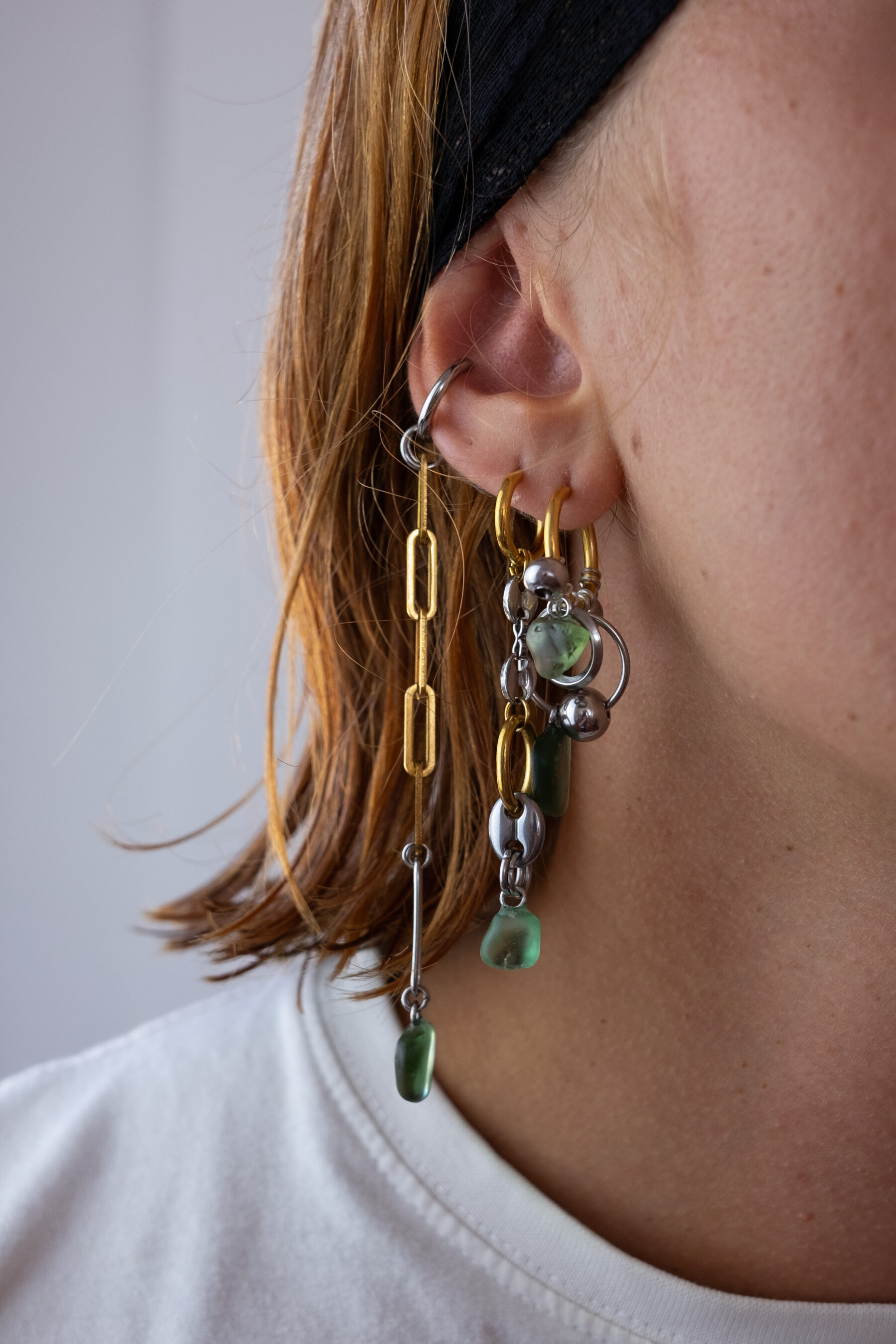 Mono boucle d’oreilles en acier inoxydable composée d’une créole doré ou argenté, et de morceaux de verre poli ramassés sur les plages du sud de la France agrémentés de chaines longues dorées ou argentées