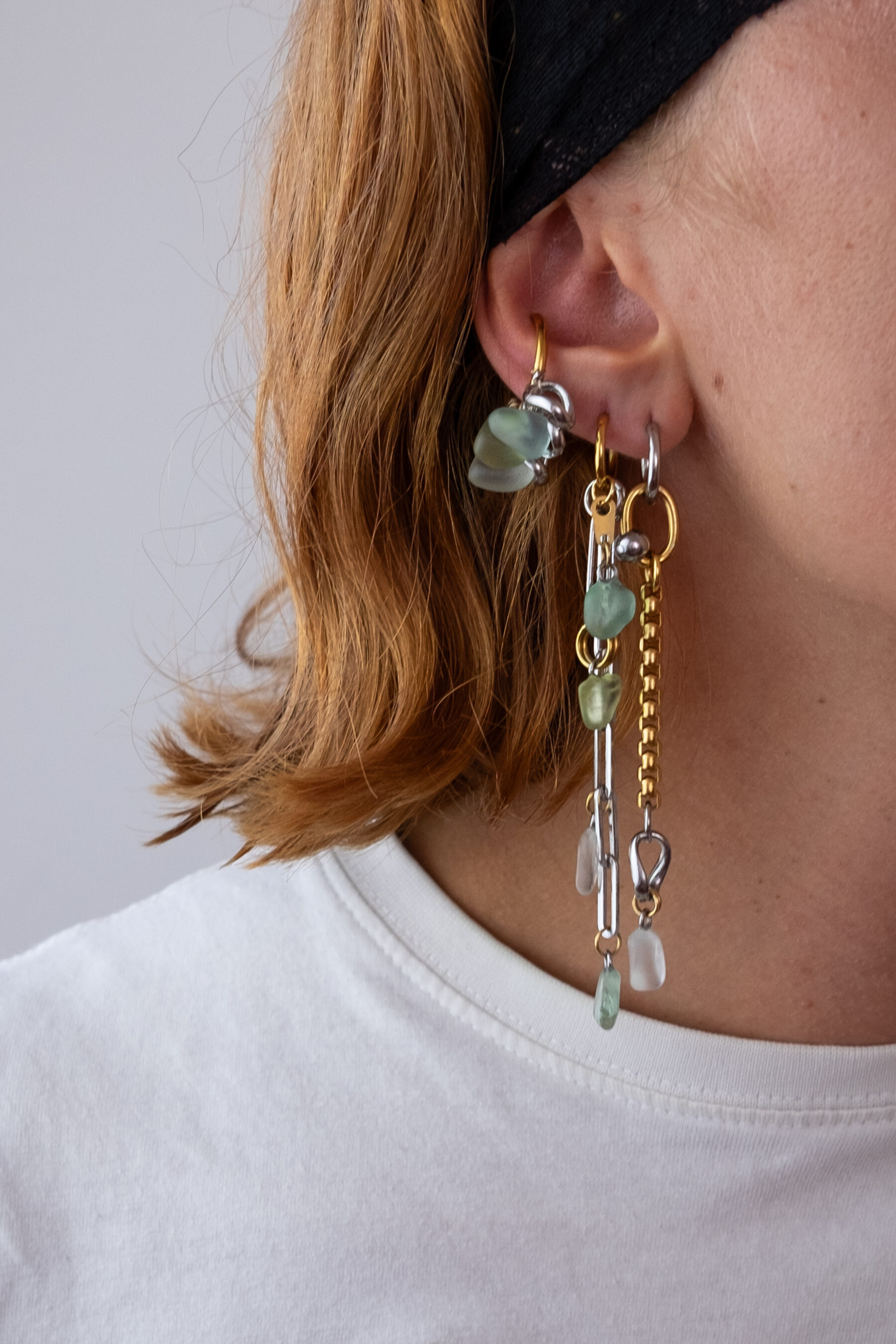 Mono boucle d’oreilles en acier inoxydable composée d’une créole doré ou argenté, et de morceaux de verre poli ramassés sur les plages du sud de la France tressés autour de la boucle