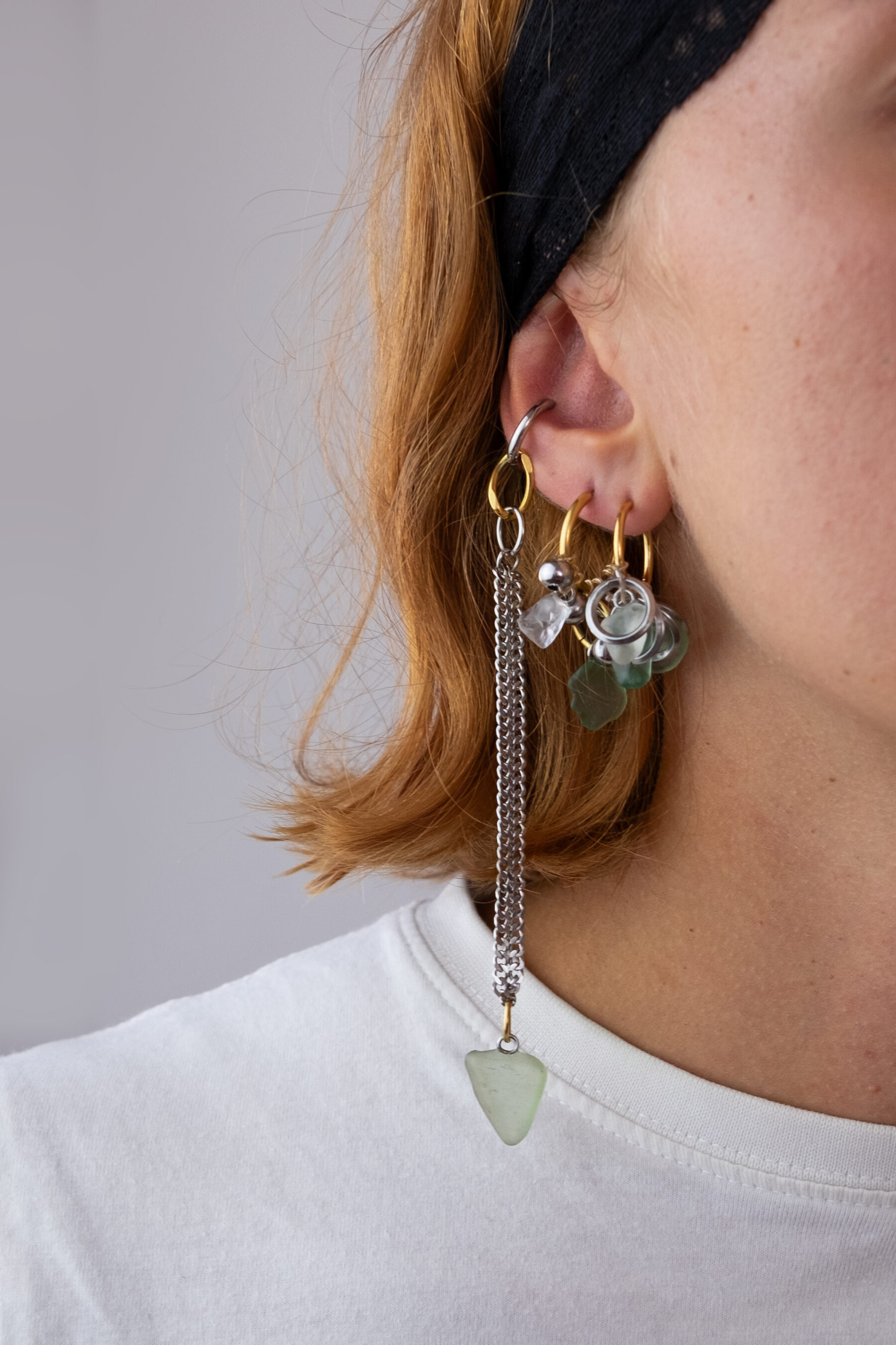 Mono boucle d’oreilles en acier inoxydable composée d’une créole doré ou argenté, et de morceaux de verre poli ramassés sur les plages du sud de la France tressés autour de la boucle