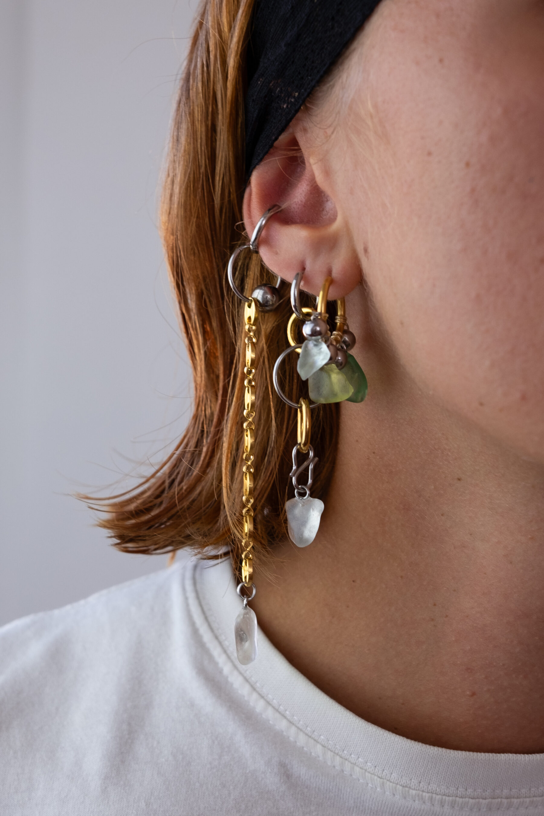 Mono boucle d’oreilles en acier inoxydable composée d’une créole doré ou argenté, et de morceaux de verre poli ramassés sur les plages du sud de la France agrémentés de chaines longues dorées ou argentées