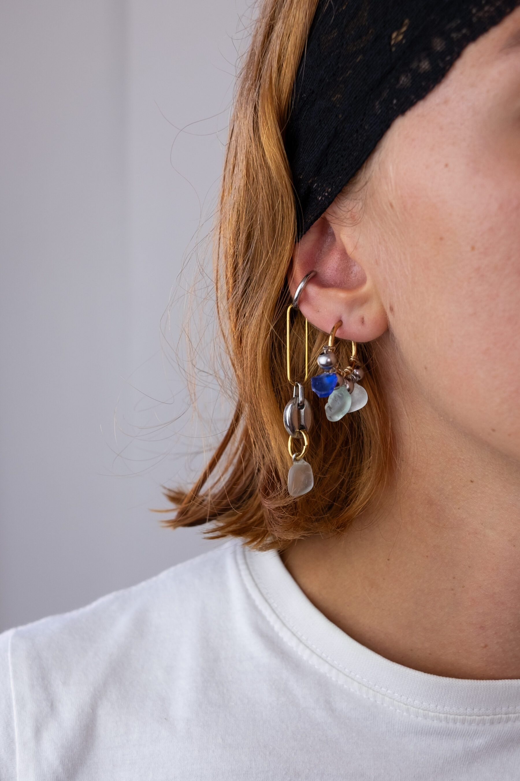Mono boucle d’oreilles en acier inoxydable composée d’une créole doré ou argenté, et de morceaux de verre poli ramassés sur les plages du sud de la France tressés autour de la boucle