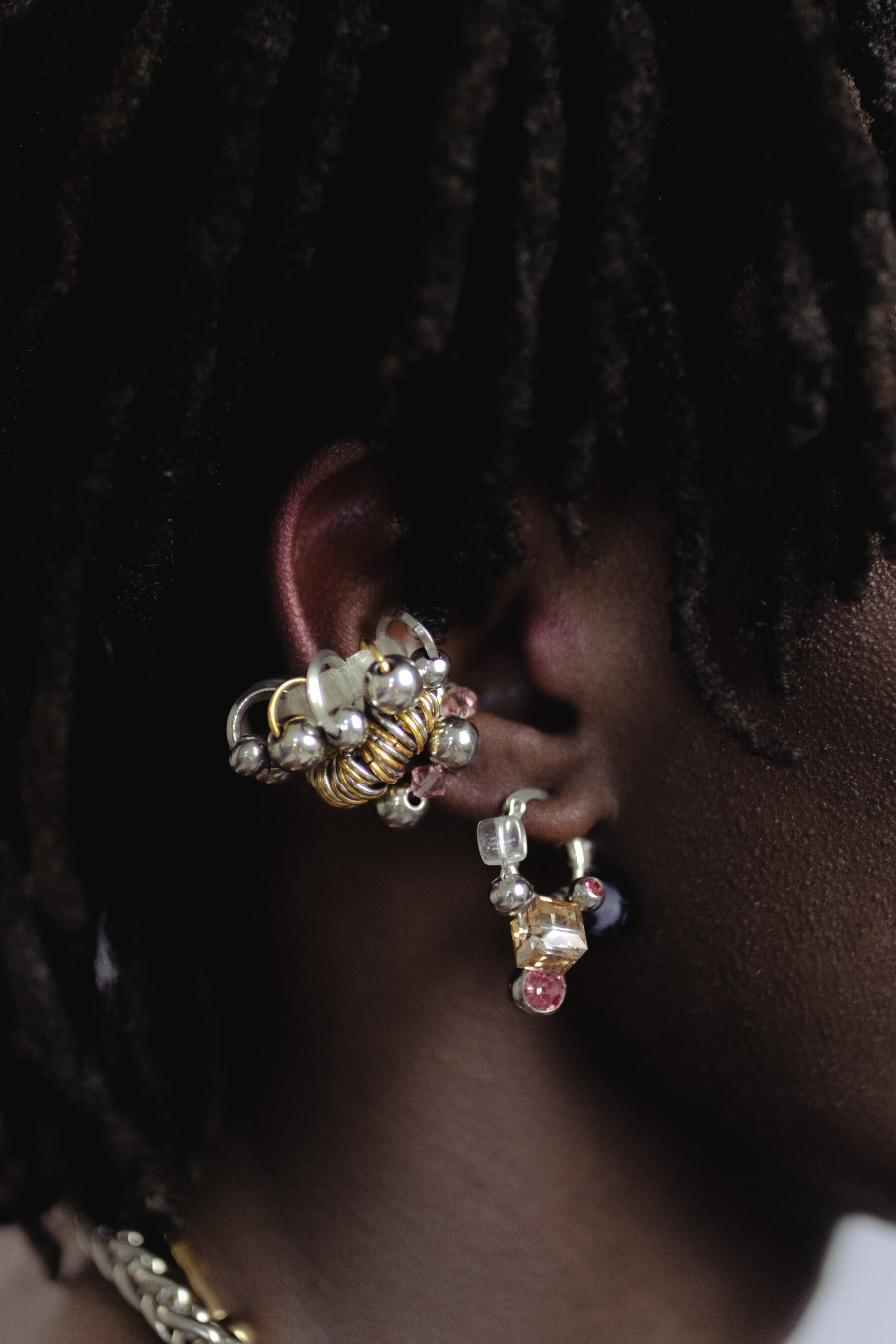 Mono boucle d’oreilles en acier inoxydable composée d’une créole argentée, de perles en cristal, en verre, et synthétique, ainsi qu'un piercing, tressés autour de la boucle
